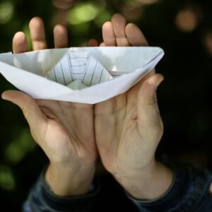 girl holding paper made ship in hand.