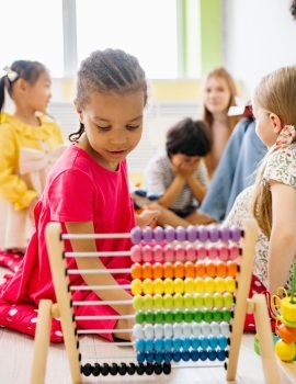 Pre school children playing and learning abacus and other games guided by teacher.